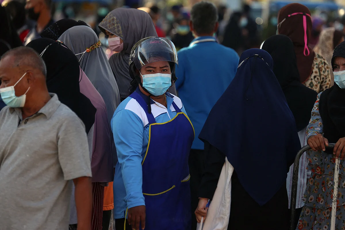 A vendor wearing a face mask and motorcycle helmet stands amongst a crowd of people visiting a fresh food market, busy for the Eid ul-Fitr festival marking the end of the Islamic holy month of Ramadan, amid concerns over the spread of the Coronavirus in Pattani on May 11, 2021.