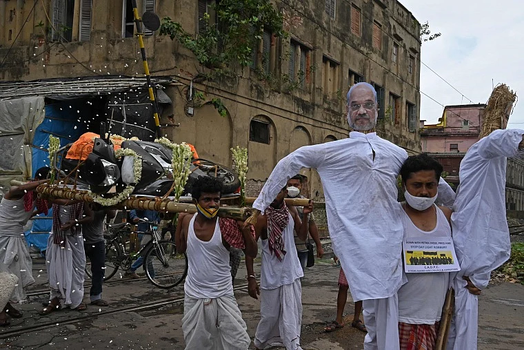 Activists mock a funeral procession of a petrol run vehicle with masks of Indian Prime Minister Narendra Modi and Indian Home Minister Amit Shah during a demonstration to protest against the rising fuel prices along a road in Kolkata