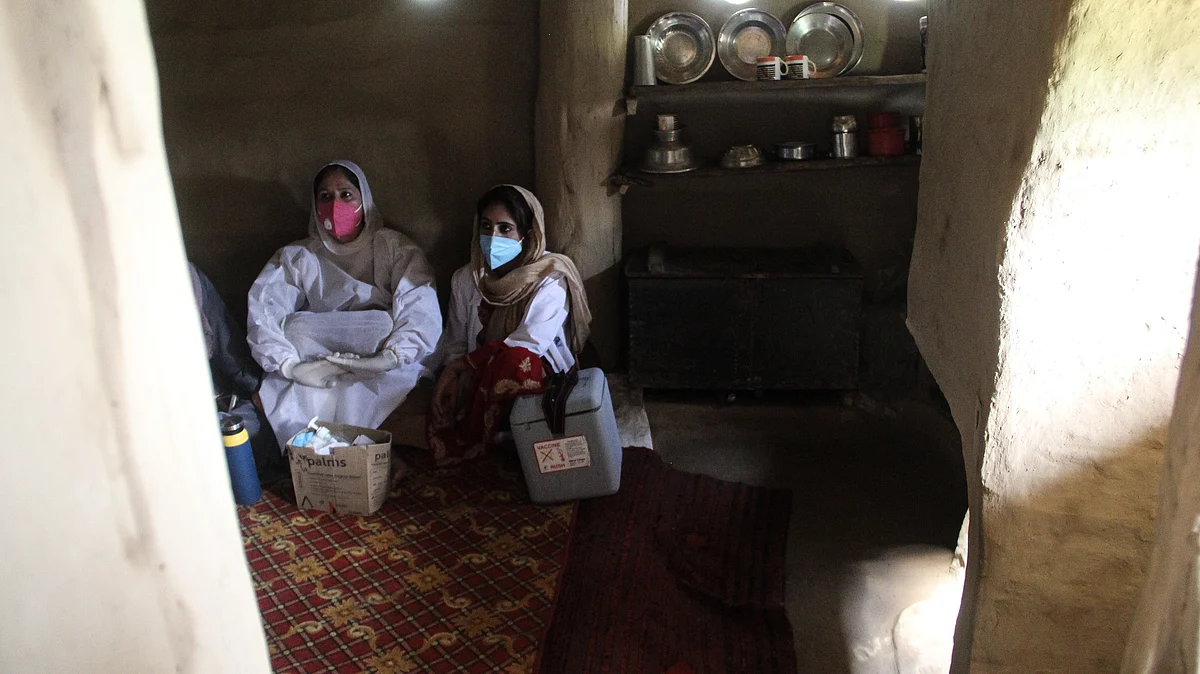 Healthcare workers rest inside a mud house during the vaccination drive in the forest area of Central kashmir's Budgam district.