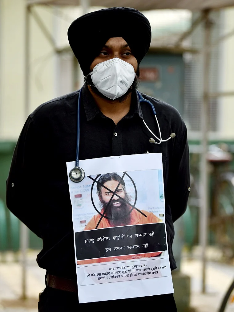 An AIIMS resident doctor holds a placard as they observe Black Day during a protest against Yog Guru Ramdevs remarks on Allopathy, in New Delhi