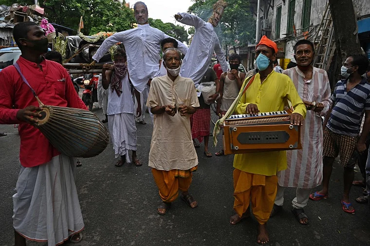 Activists mock a funeral procession of a petrol run vehicle with masks of Indian Prime Minister Narendra Modi and Indian Home Minister Amit Shah during a demonstration to protest against the rising fuel prices along a road in Kolkata