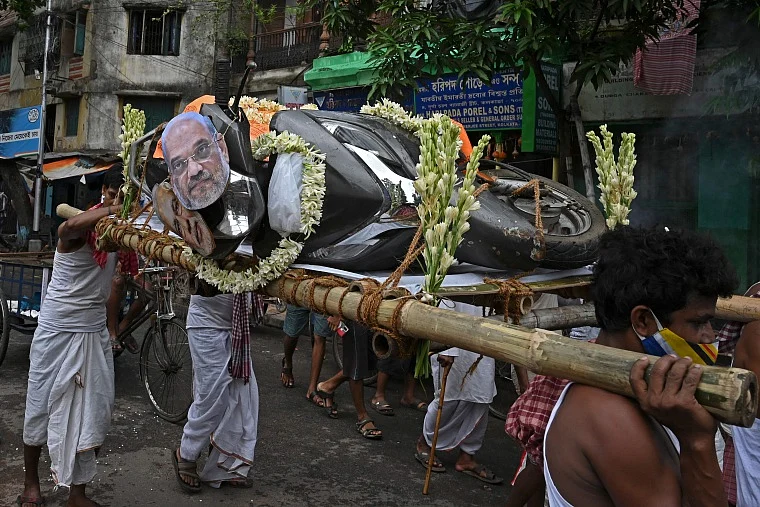 Activists mock a funeral procession of a petrol run vehicle with masks of Indian Prime Minister Narendra Modi and Indian Home Minister Amit Shah during a demonstration to protest against the rising fuel prices along a road in Kolkata
