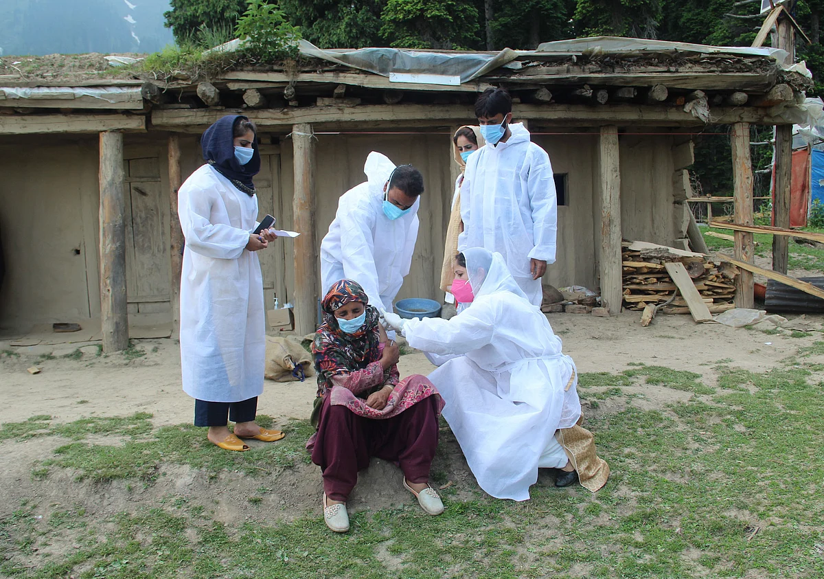 A healthcare worker gives a dose of Covishield, a coronavirus disease (COVID-19) vaccine to a nomadic woman during a vaccination drive in the forest area of Central Kashmir's Budgam district.