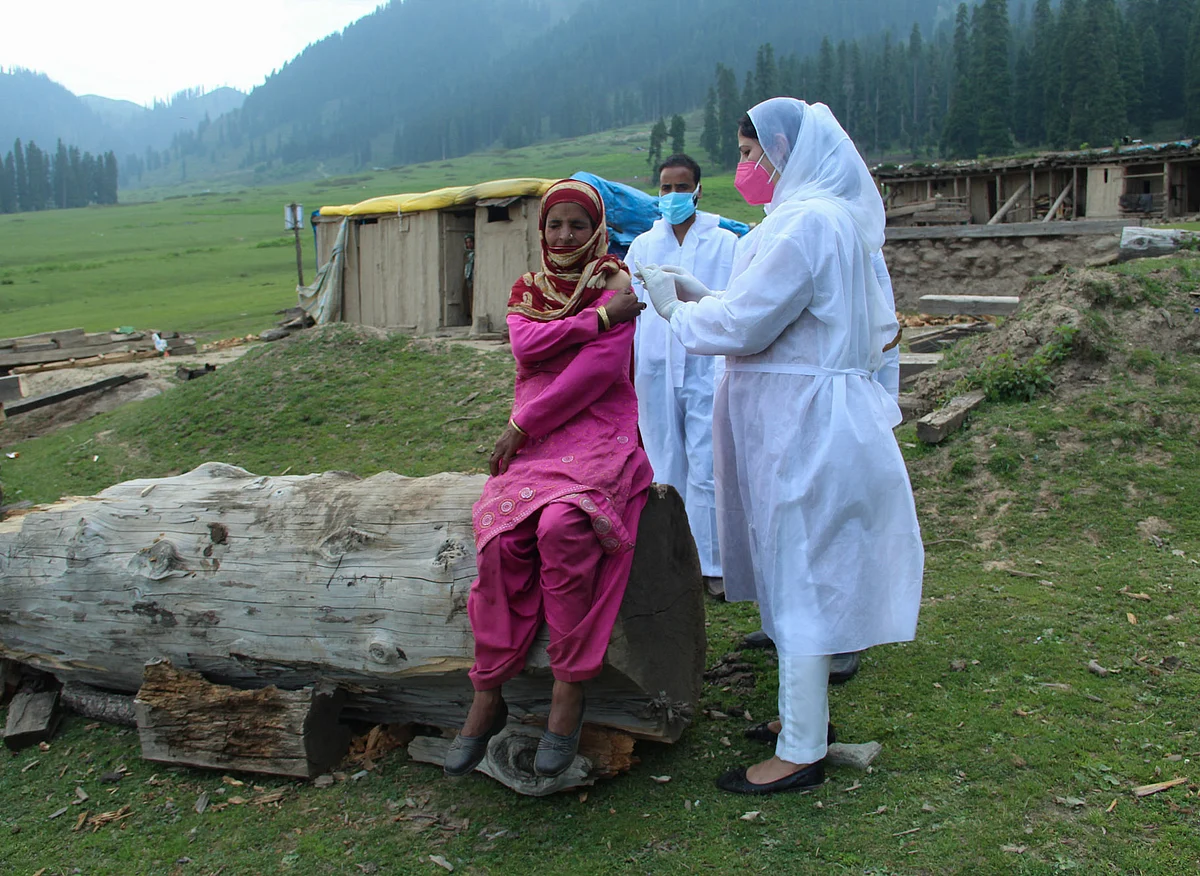 A healthcare worker gives a dose of Covishield, a coronavirus (COVID-19) vaccine to a nomadic woman during a vaccination drive in the forest area in Central Kashmir's Budgam district.