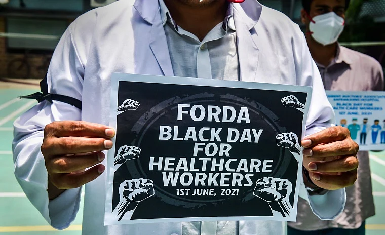 A doctor shows a placard during Black Day Protest by Federation of resident doctors associations (FORDA) and Resident doctors Association (RDA) Safdarjung Hospital, against Baba Ramdev for his comments on allopathy, in New Delhi,
