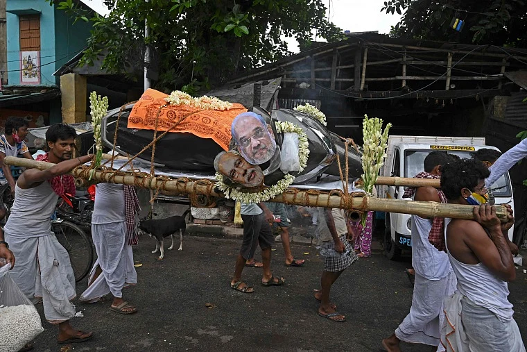 Activists mock a funeral procession of a petrol run vehicle with masks of Indian Prime Minister Narendra Modi and Indian Home Minister Amit Shah during a demonstration to protest against the rising fuel prices along a road in Kolkata