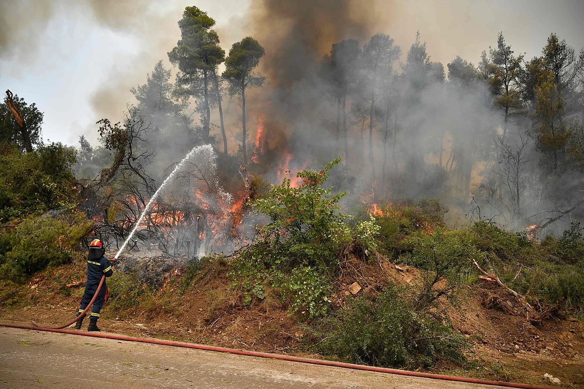 Fire crews spray water in an attempt to build a controlled fire zone to prevent the blaze to reach the village of Kechries in North Evia, on August 5, 2021. - The blazes in Greece this week briefly cut off the main road leading to Athens and saw worrying fires break out in Olympia -- the birthplace of the Olympic Games that is usually crowded with tourists -- and on the island of Evia.