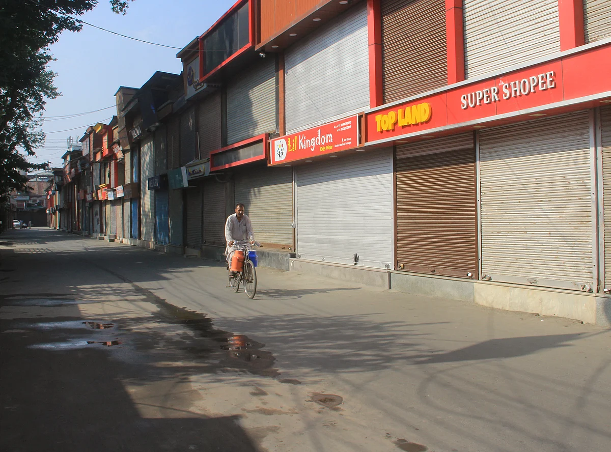 A milkman rides his bicycle through a deserted street during a shutdown on the second anniversary of abrogation of Article 370 & 35A in Srinagar, Jammu & Kashmir on August 5, 2021.