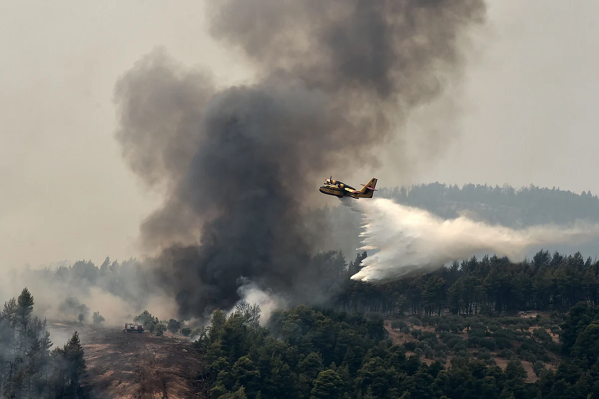 A water-bombing aircraft pours water on a wildfire on August 5, 2021, near the village of Kechries in North Evia. - The blazes in Greece this week briefly cut off the main road leading to Athens and saw worrying fires break out in Olympia -- the birthplace of the Olympic Games that is usually crowded with tourists -- and on the island of Evia.