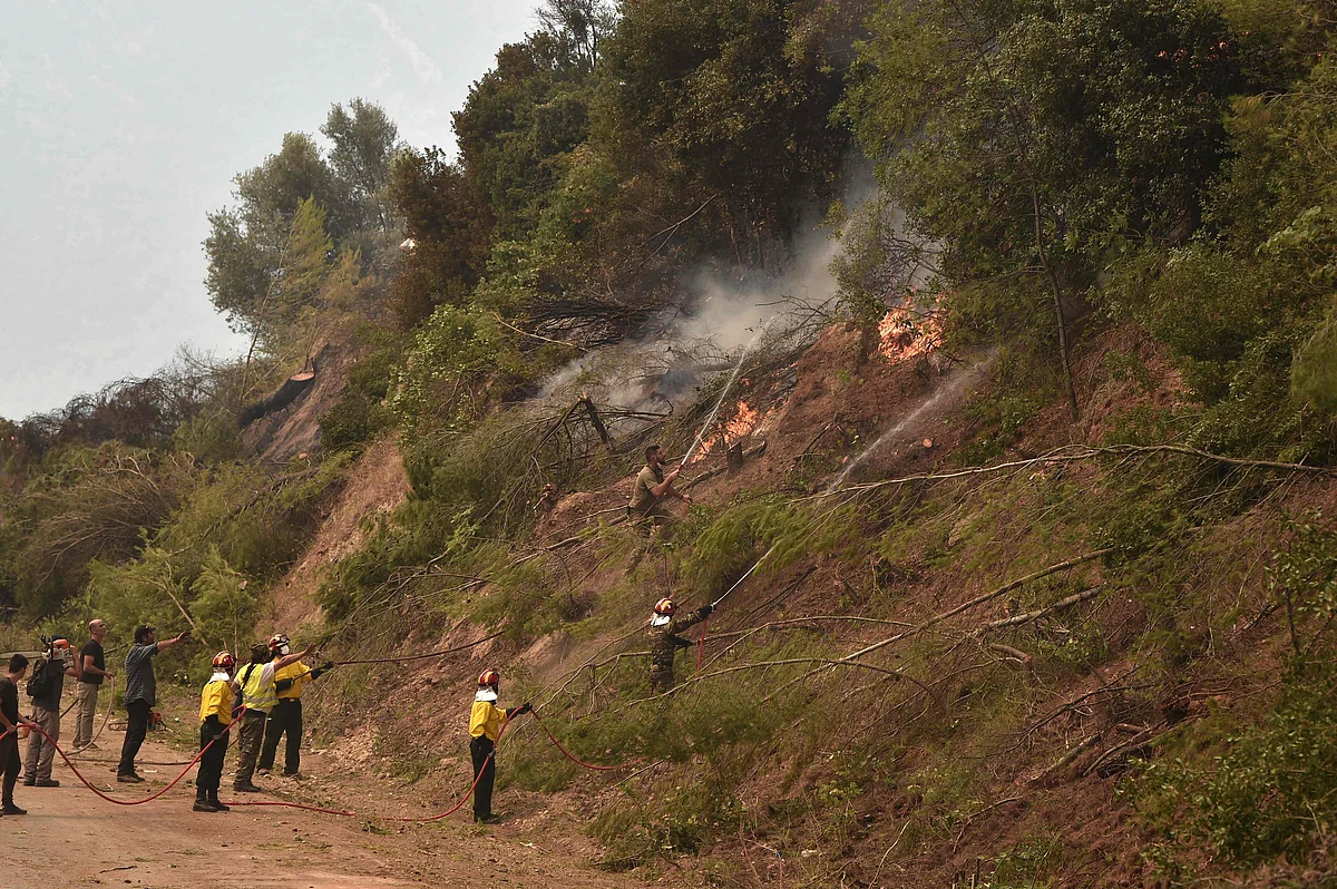 Fire crews spray water in an attempt to build a controlled fire zone to prevent the blaze to reach the village of Kechries in North Evia, on August 5, 2021, near. - The blazes in Greece this week briefly cut off the main road leading to Athens and saw worrying fires break out in Olympia -- the birthplace of the Olympic Games that is usually crowded with tourists -- and on the island of Evia.