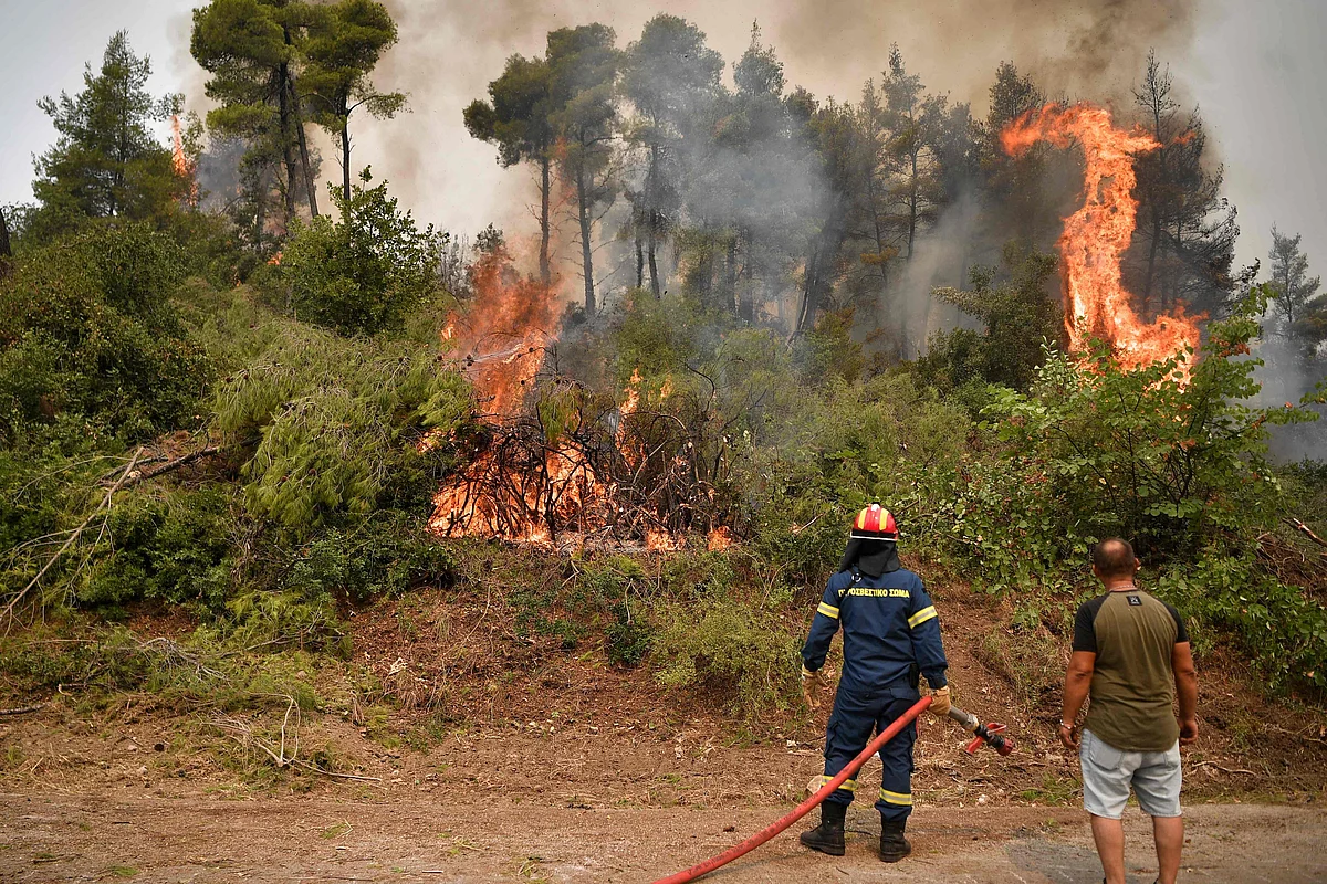 Fire crews spray water in an attempt to build a controlled fire zone to prevent the blaze to reach the village of Kechries in North Evia, on August 5, 2021, near. - The blazes in Greece this week briefly cut off the main road leading to Athens and saw worrying fires break out in Olympia -- the birthplace of the Olympic Games that is usually crowded with tourists -- and on the island of Evia.