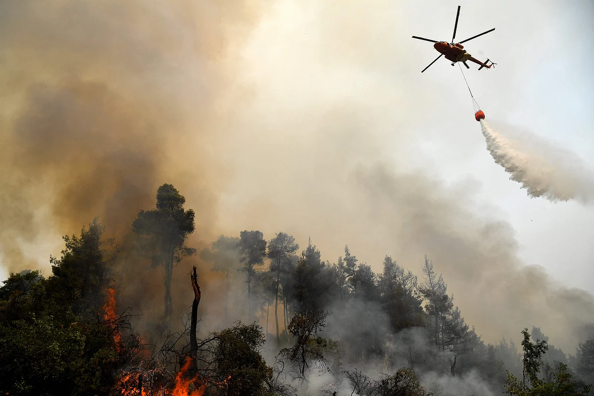 A helicopter pours water on a wildfire on August 5, 2021, near the village of Kechries in North Evia. - The blazes in Greece this week briefly cut off the main road leading to Athens and saw worrying fires break out in Olympia -- the birthplace of the Olympic Games that is usually crowded with tourists -- and on the island of Evia.