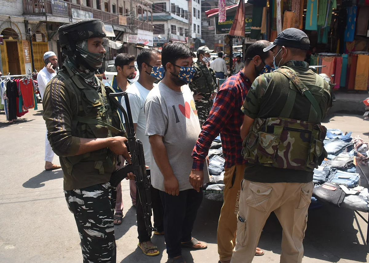 Policeman frisked citizens a Kashmiri man as other wait in queue for their turn during a surprise cordon and search operation (CASO)