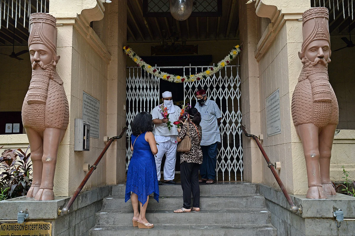A Parsi priest (C) hands over the flowers to women at the fire temple on the occasion of Parsi New Year in Mumbai on August 16, 2021.