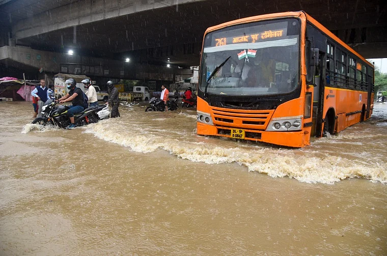Vehicles wade through a waterlogged road during heavy rainfall