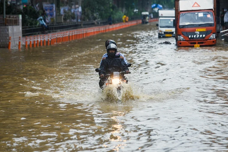 Vehicles wade through a waterlogged road during heavy rainfall