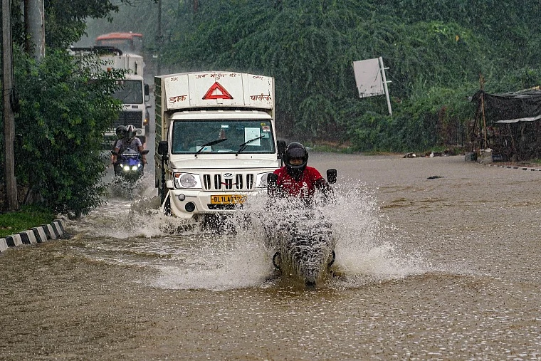 Vehicles wade through a waterlogged road during heavy rainfall