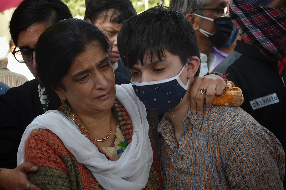 Wife of Makhan Lal Bindroo, a prominent pharmacist, mourns around his body along with other relatives during his funeral at his residence in Srinagar, Kashmir on Wednesday, October 6, 2021.