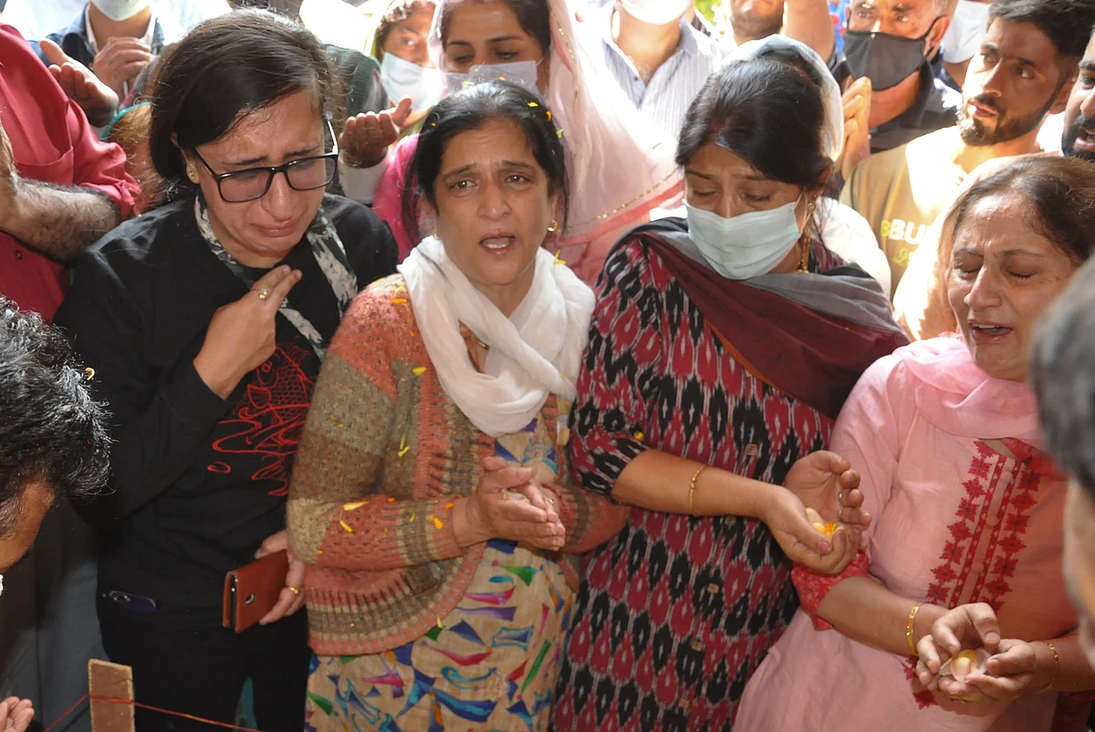 Daughter Shraddha (L), wife (2L) of Makhan Lal Bindroo, a prominent pharmacist, mourns around his body along with other relatives during his funeral at his residence in Srinagar, Kashmir on Wednesday, October 6, 2021.