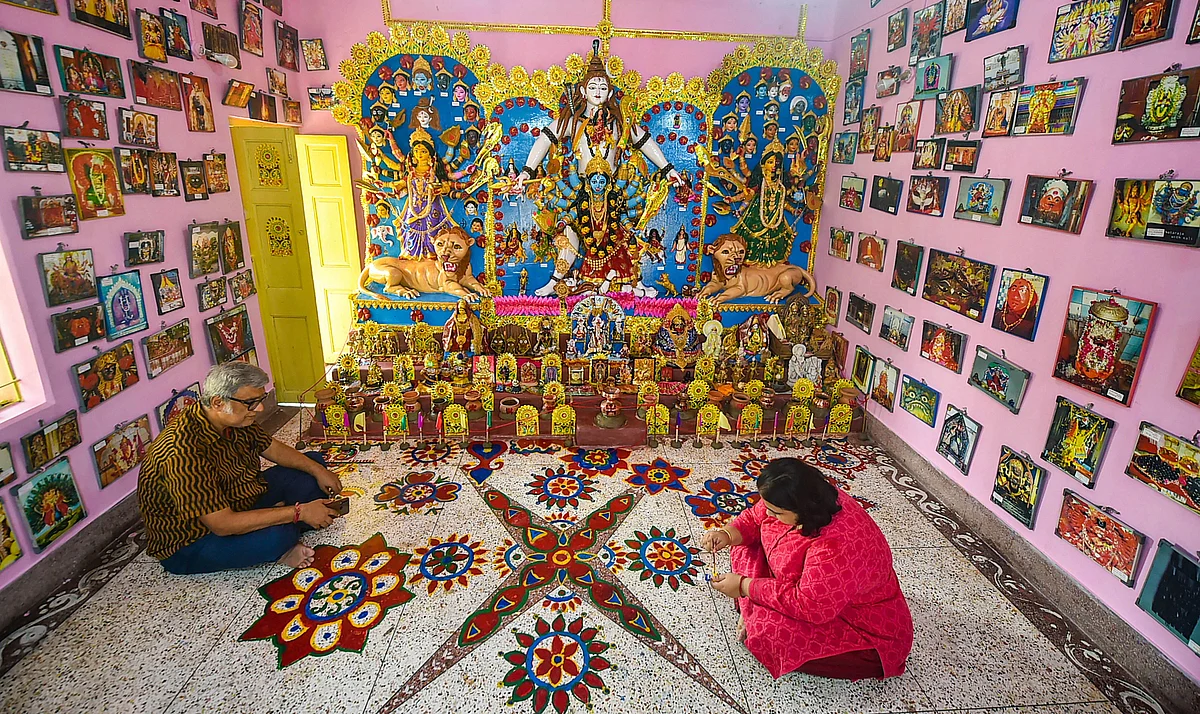 robir Kumar Misra looks on as his daughter prepares a rangoli on the floor ahead of Durga Puja festival, at his residence cum museum in Kolkata, Monday, Oct 4, 2021. Shakti Mata Devi vishwadarshan is an iconic mythological unique museum that houses in 422 forms, icarnations and shrines of Goddess Shakti located all across the universe. The collection spreads 27 countries and is the first of its own kind. All deities are framed under the same roof in one one room. Deities include idols of Nava Durga, Nava Ratri Shakti Mata and Dusmahavidya. The museum cum residence located in New Alipore, South Kolkata.
