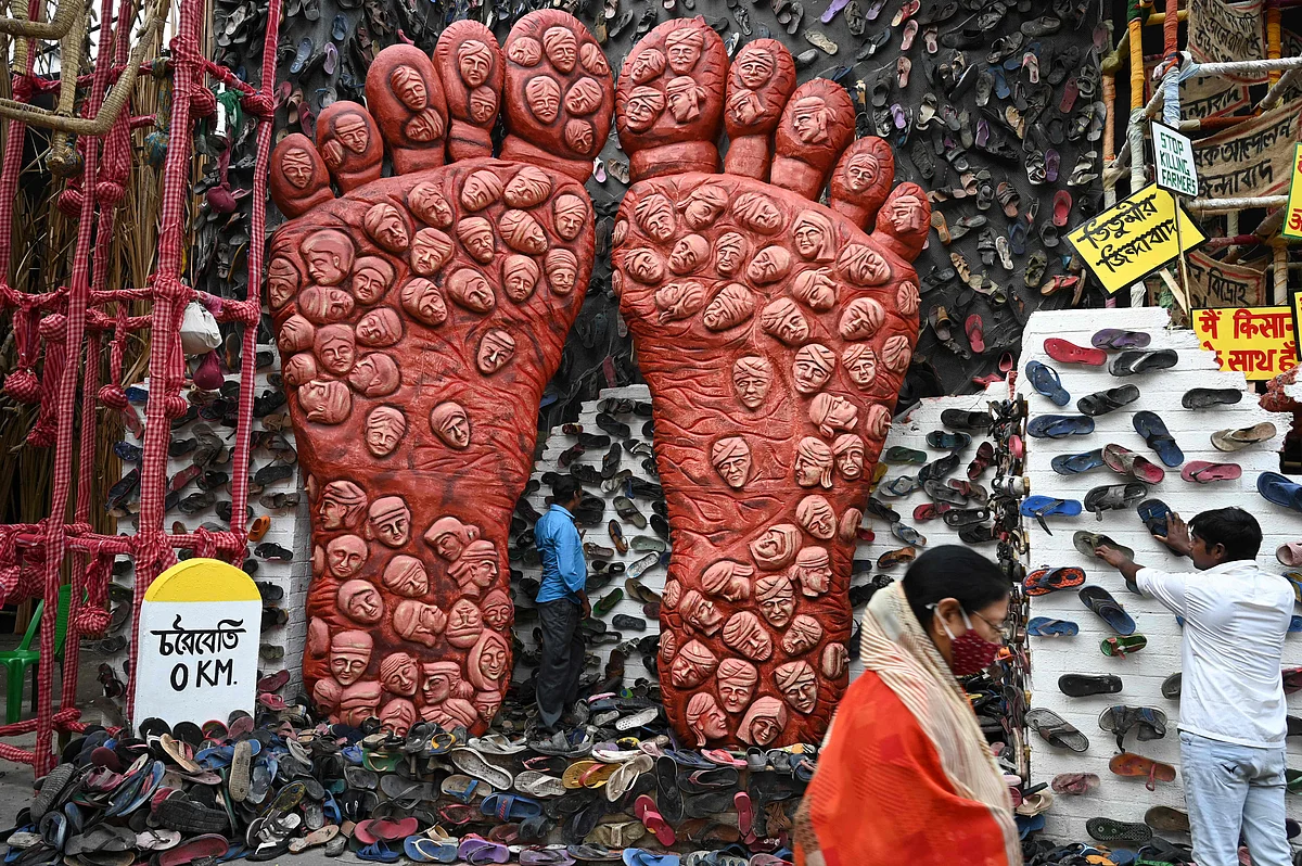 person walk past workers decorating of a makeshift place of worship for Durga Puja with a theme in support the ongoing farmers protest against the central governments agricultural reforms, in Kolkata on October 6, 2021.