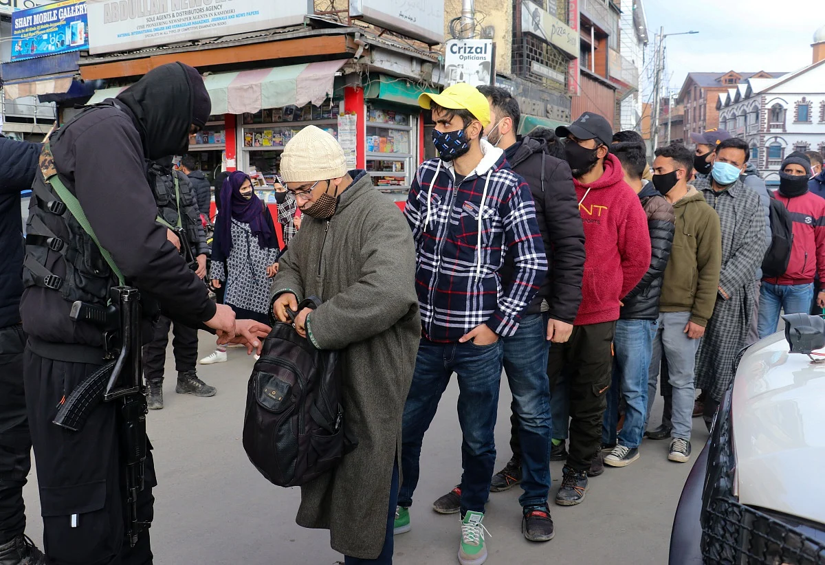 Policemen frisk a Kashmiri man as other wait for their turn after a grenade attack by suspected militants in Srinagar.