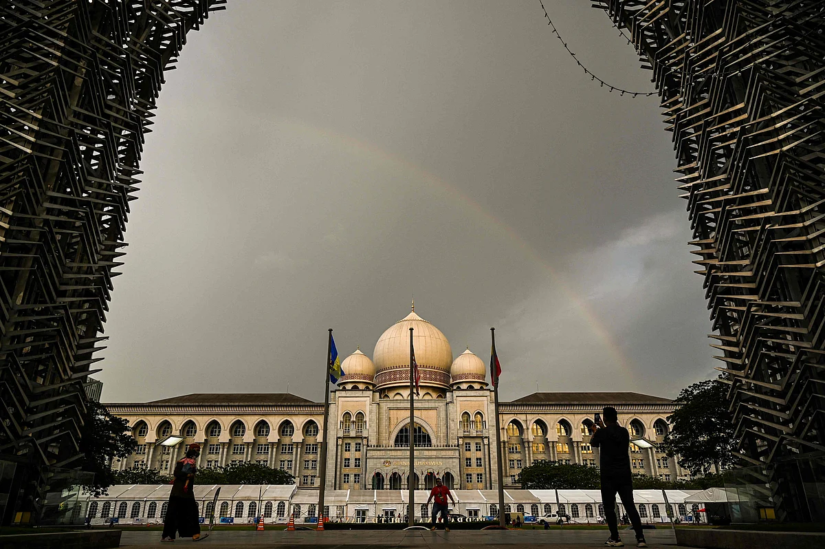 TOPSHOT - People take pictures of a rainbow over The Palace of Justice on the eve of the Islamic holy month of Ramadan in Putrajaya on April 2, 2022. (Photo by Mohd RASFAN / AFP)