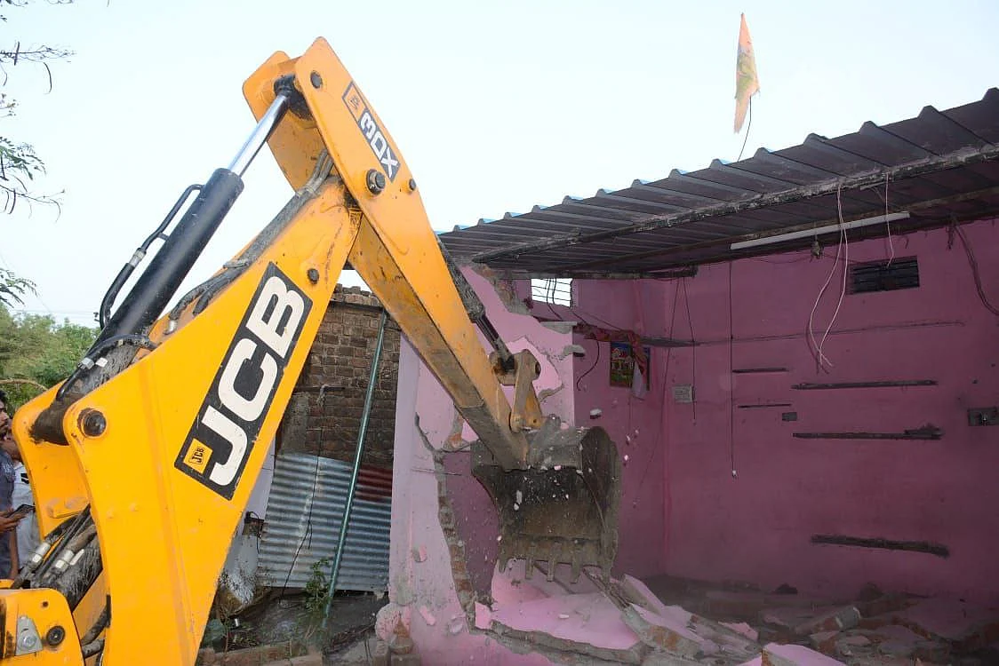 A JCB machine razing illegal constructions made on government land, in Ujjain on Tuesday.
