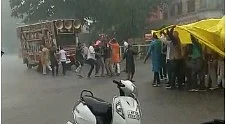 A wedding procession taken out in the rain under tarpaulin cover