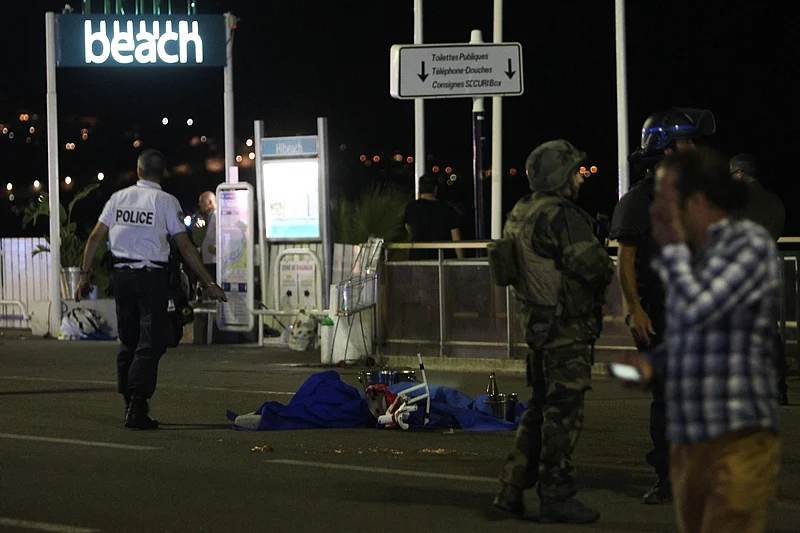 A police officer stands next to a dead body covered with a blue sheet on the Promenade des Anglais seafront in the French Riviera town of Nice on July 15, 2016, after a van drove into a crowd watching a fireworks display.<br />At least 75 people were killed when a truck drove into a crowd watching a fireworks display in the French resort of Nice, a lawmaker said on July 15. / AFP PHOTO / VALERY HACHE