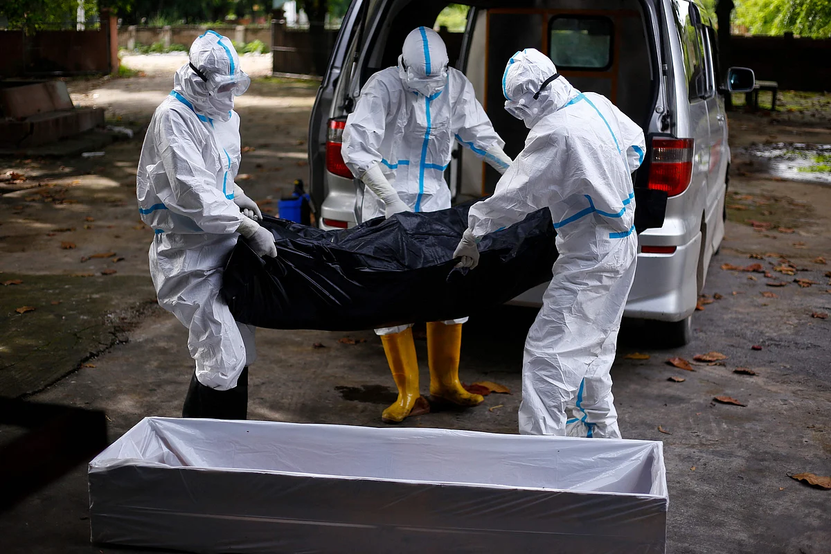 Volunteers wearing personal protective equipment (PPE) carry the body of a person who died from the Covid-19 coronavirus into a coffin before the cremation process in Taungoo, Bago region on July 8, 2021 (AFP)