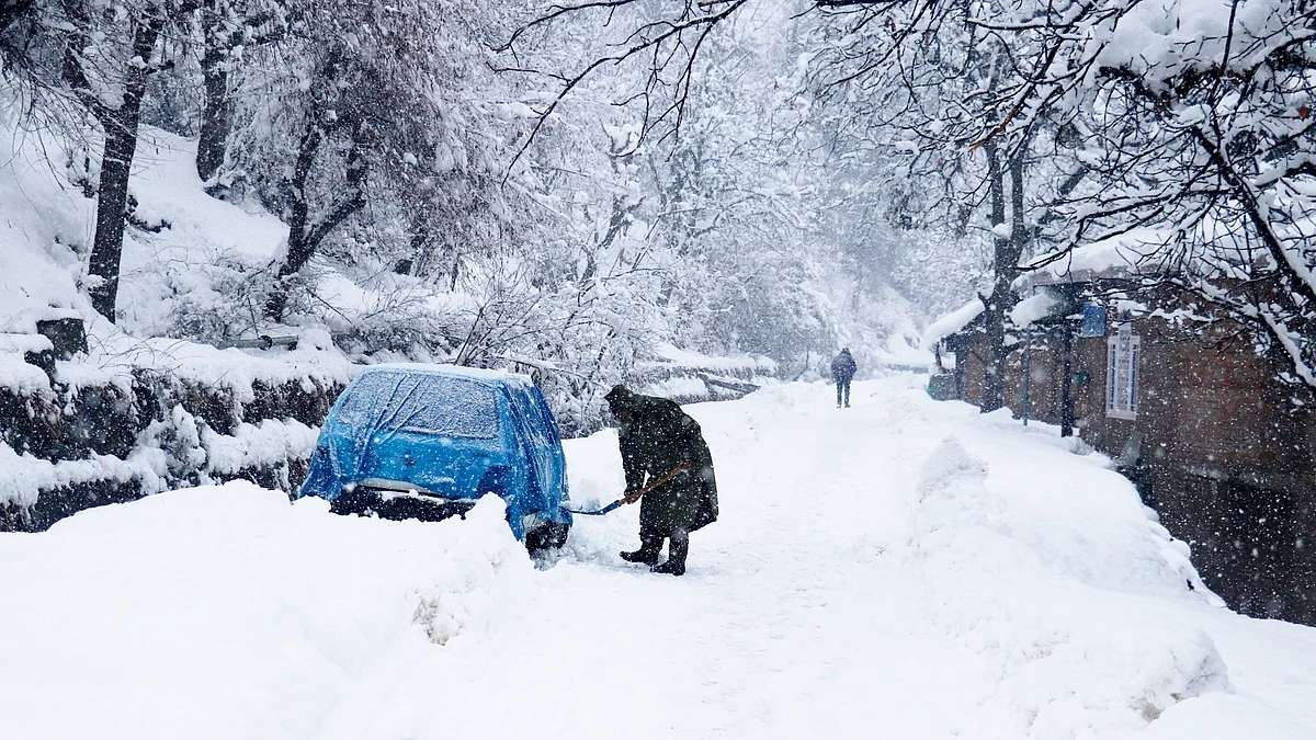 A man shovels snow to get out a snowed in car in north Kashmir's Baramulla district on Wednesday January 5, 2022.