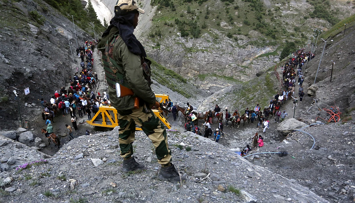 A security personnel keeps watch as Hindu devotees trek along mountains near Baltal area towards Amarnath cave.