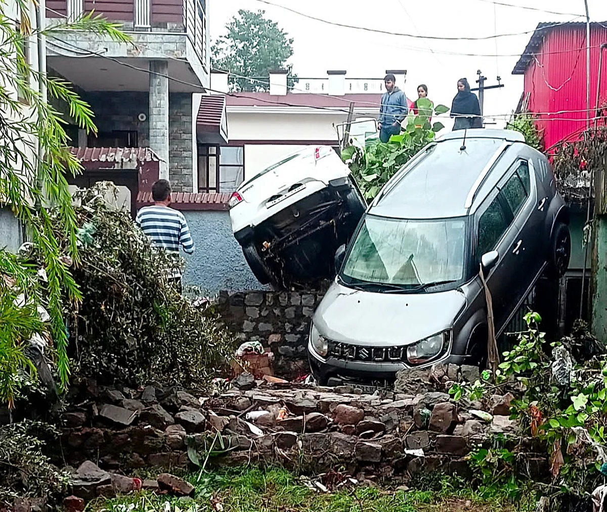 Partially damaged vehicles clung to the wall of a residential building as flood waters recede in Poonch' district's Surankote.