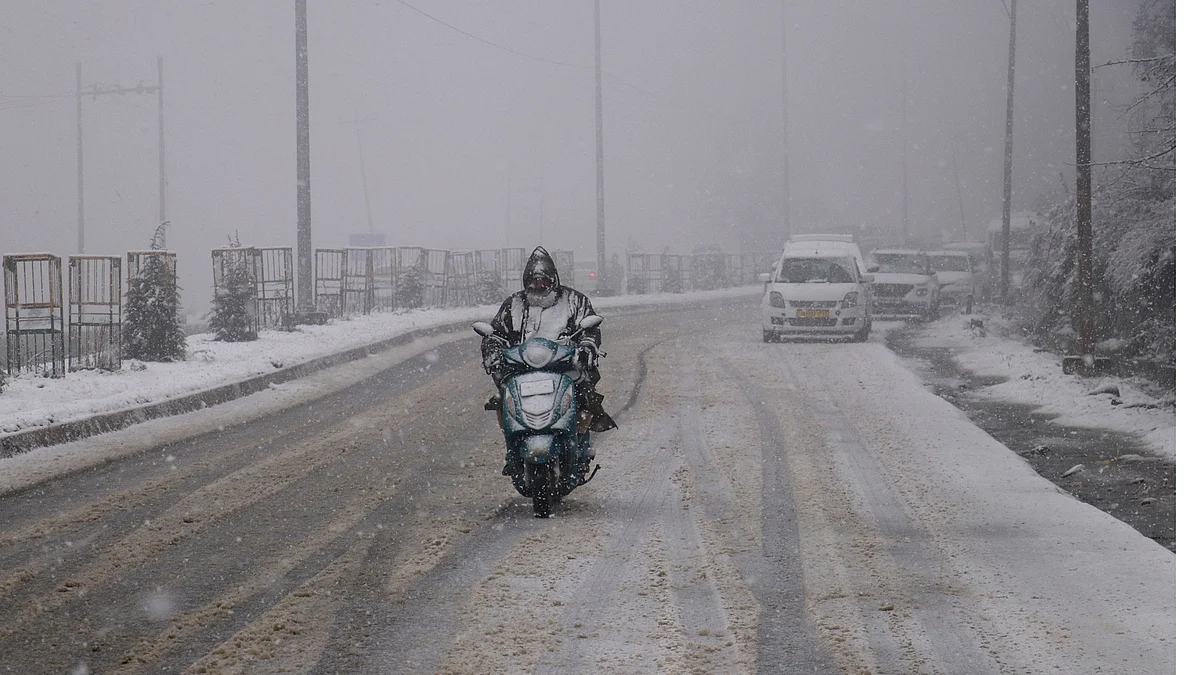 A man rides a two-wheeler amid snow in north Kashmir's Tangmarg area on Monday, 14 November 2022.