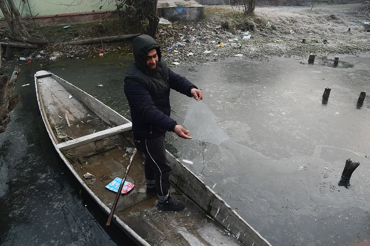 A boatman shows a piece of ice picked up from the partially frozen lake water in the interiors of Dal Lake, in Srinagar on Wednesday.