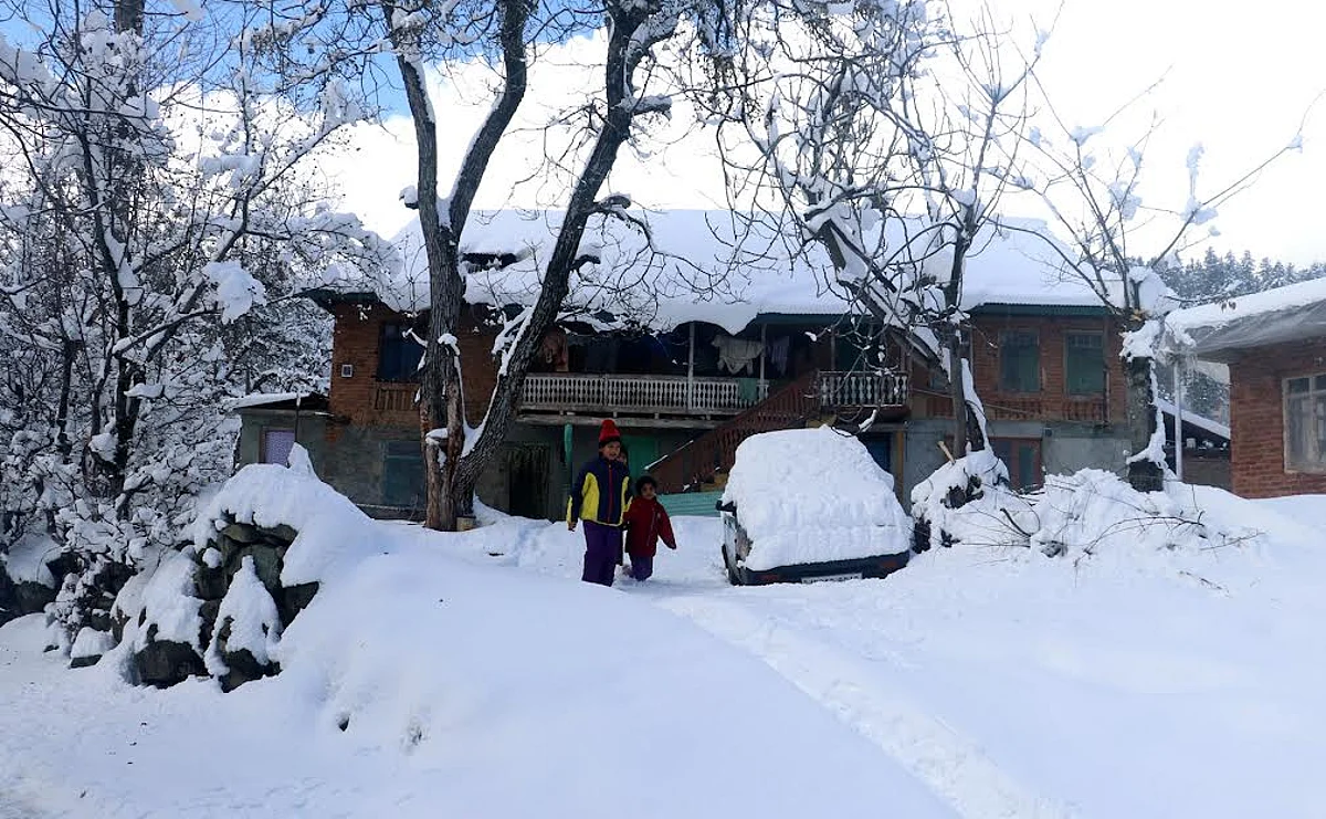 Kids are seen walking on a snow-blanketed road in north Kashmir's Tangmarg area, on Sunday 15, January 2023.