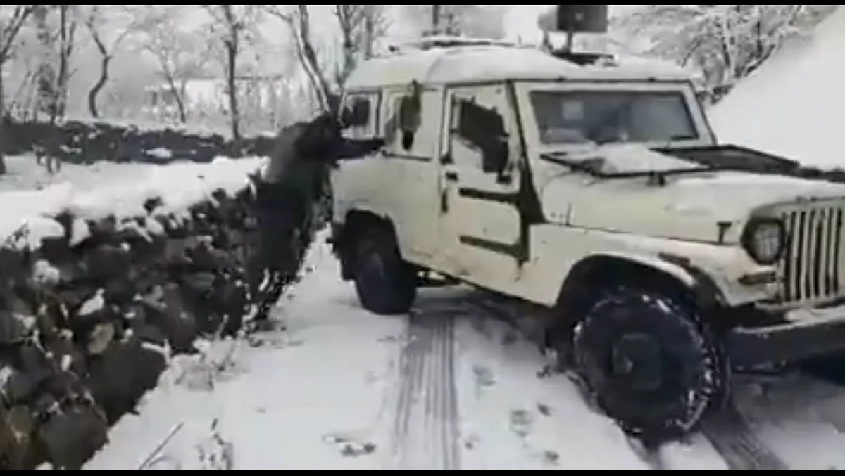 security forces push a police jeep after it skidded amid snowfall while on its way to rescue stuck people in Ganderbal's Chount Waliwar.