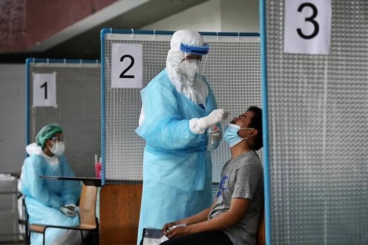 A medical worker wearing personal protective equipment (PPE) takes a nasal swab sample from a man to test for the Covid-19 coronavirus at the Thai-Japanese Stadium, also known as the Bangkok Youth Center, in Bangkok on April 27, 2021. (Photo by Lillian SUWANRUMPHA / AFP) (Photo by LILLIAN SUWANRUMPHA/AFP via Getty Images)