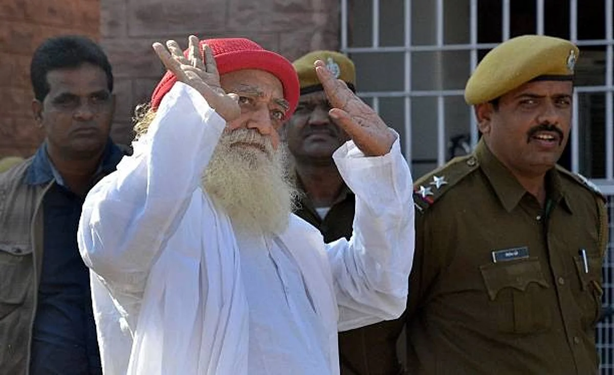JODHPUR, INDIA - NOVEMBER 18: Asaram Bapu, Hindu preacher gestures to media persons as he returns after being produced at session court in connection with the case of sexual assault of a minor on November 18, 2013 in Jodhpur, India. Court dismissed as withdrawn the petitions moved by controversial self-styled godman Asaram. (Photo by Ramji Vyas/Hindustan Times via Getty Images)