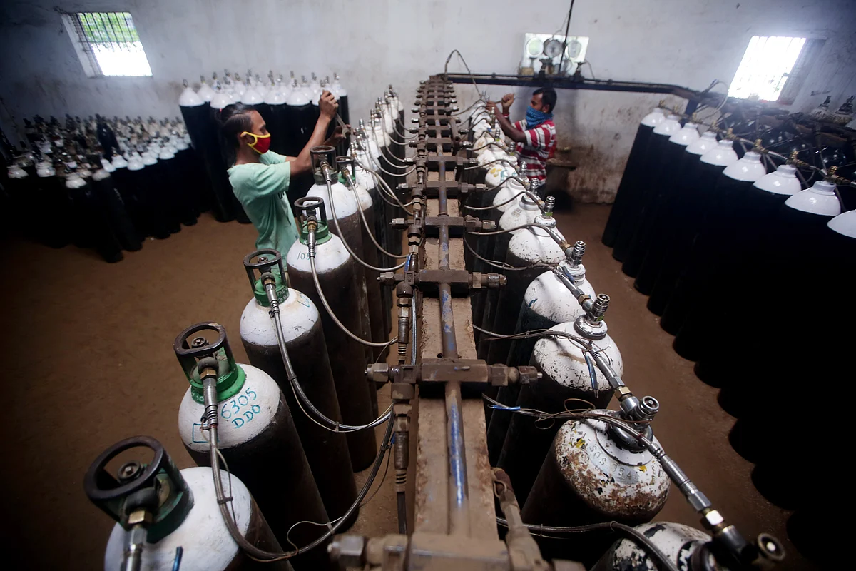 Workers refilling oxygen cylinders at a medical oxygen gas manufacturing and refilling unit. An effective vaccine rollout by the government could result in an annual outlook which is balanced with a limited downside.