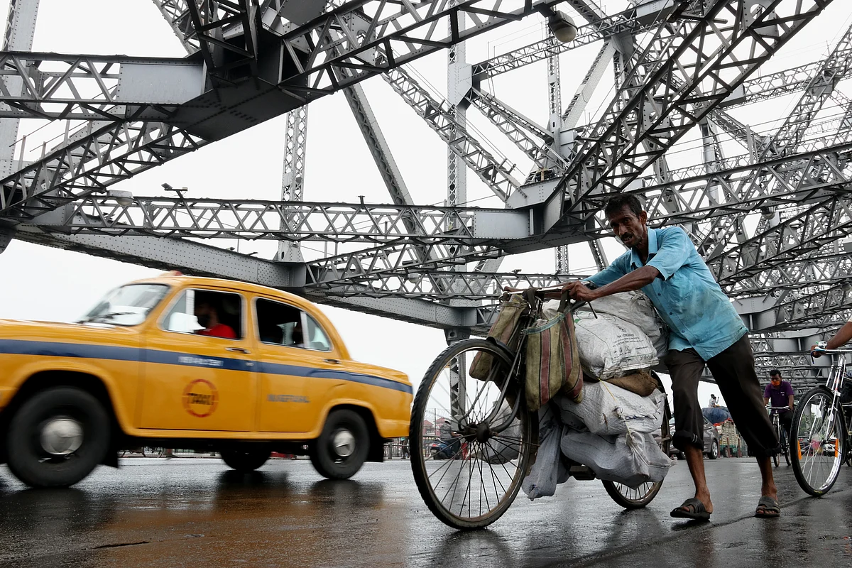 Commuters carry goods past the Howrah Bridge over the Hooghly River. Fuel prices in India have are going through regular hikes but they are not issues that can be moderated through monetary policy measures.