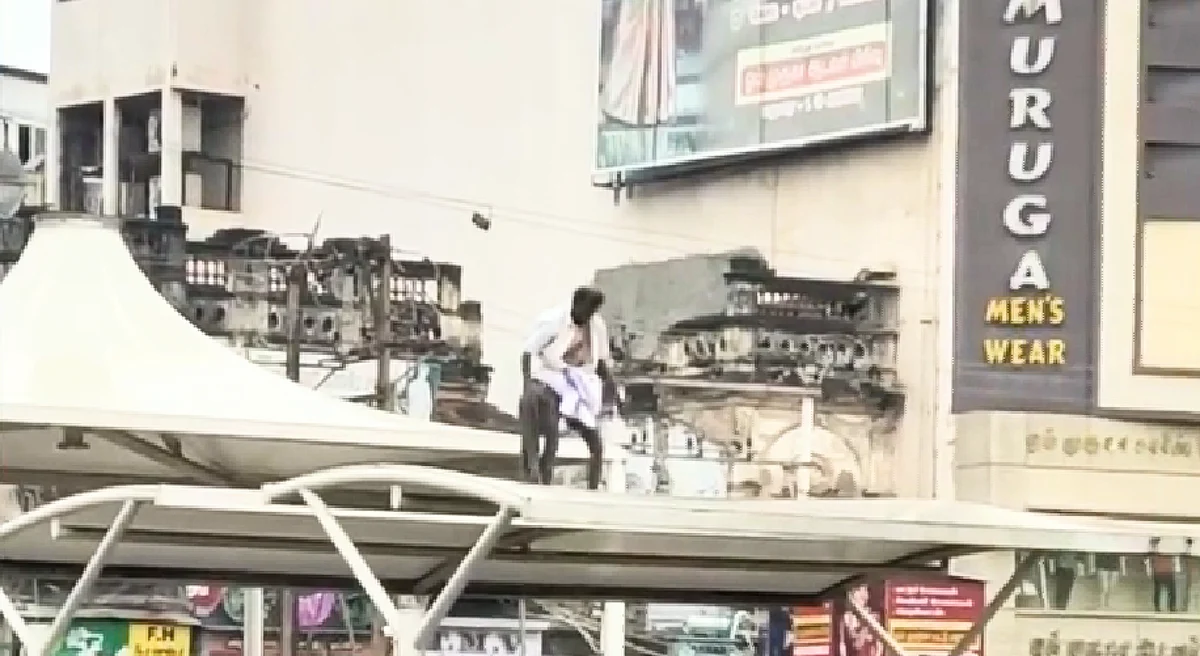 நிழற்குடையின் மேல் இருந்து குதிக்கும் முதியவர்