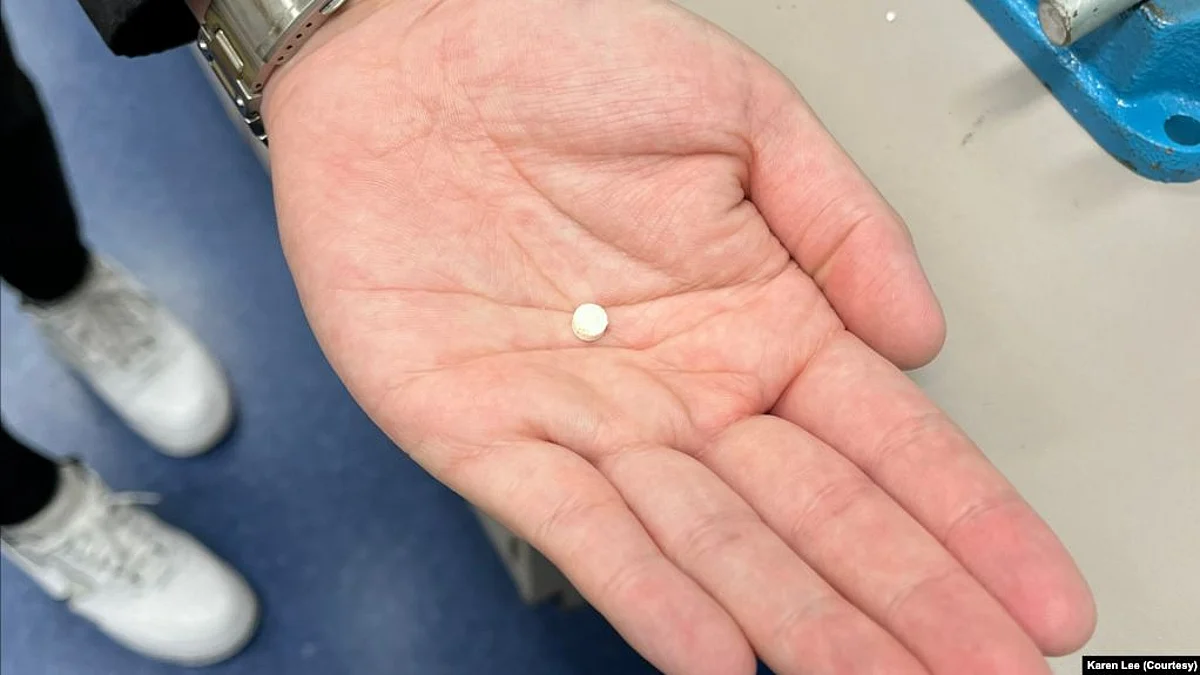 University of British Columbia research student Yigong Guo holds a small-sized insulin tablet. (Image source- VOA)