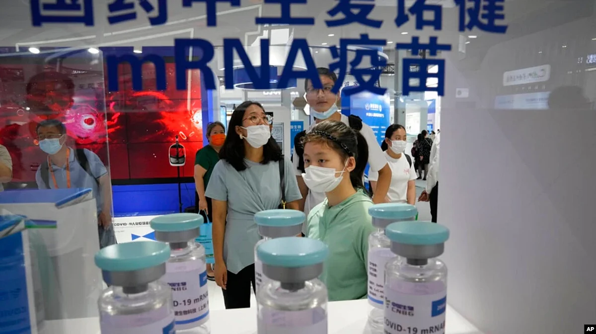 FILE - Visitors look at giant replica bottles of COVID-19 vaccine produced by Sinopharm subsidiary CNBG using mRNA technologies at the China International Fair for Trade in Services in Beijing, China, Sept. 5, 2021.