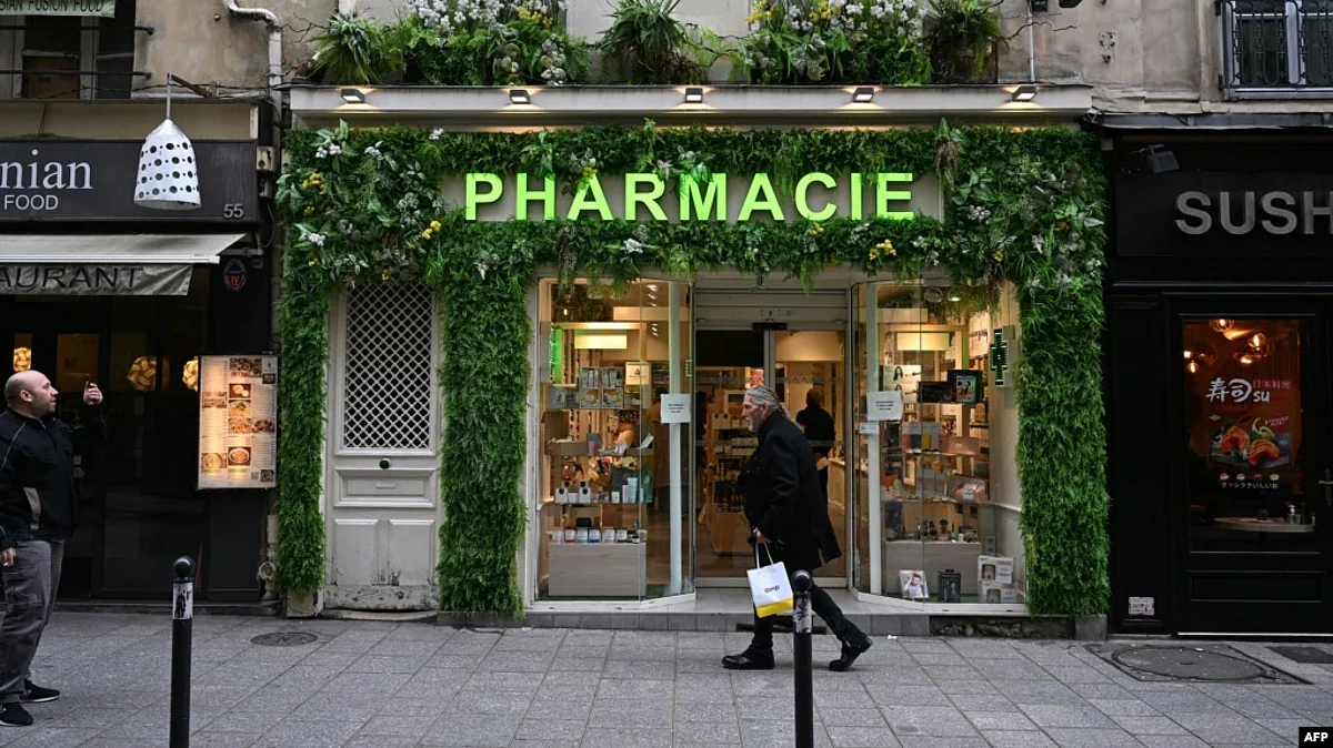 FILE - Men walk past a pharmacy in Paris, France, Nov. 24, 2022. As of Jan. 1, 2023, pharmacies in the country will be stocking free condoms for anyone under the age of 25.