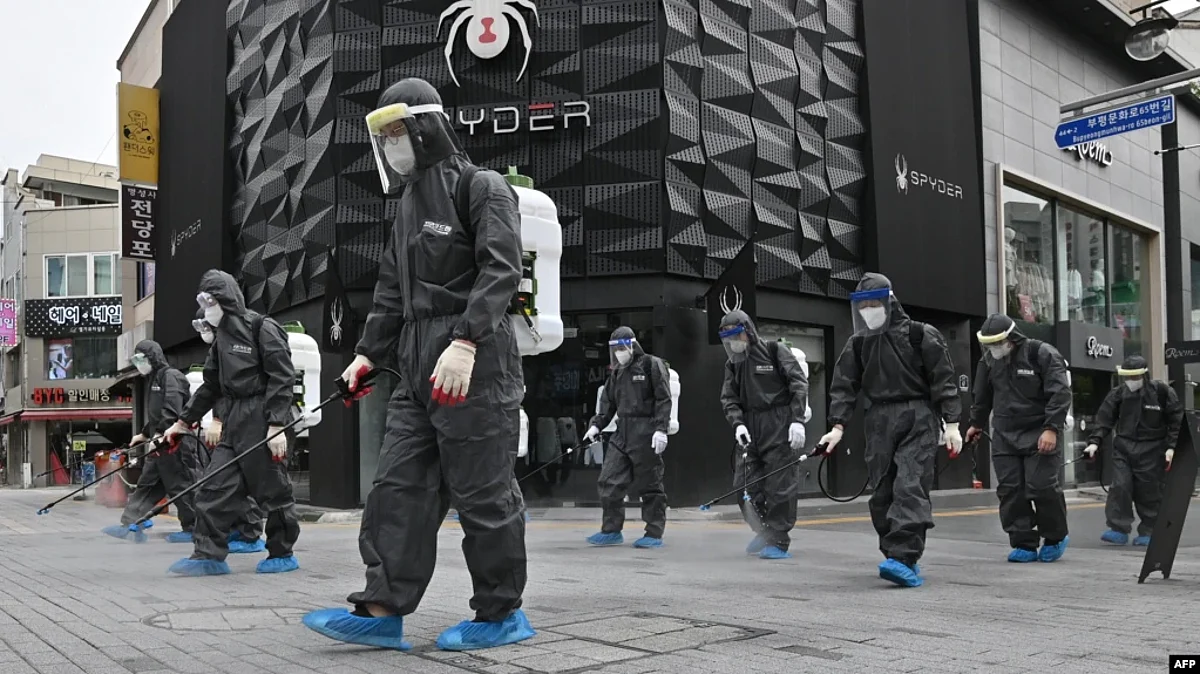 FILE - South Korean health officials from Bupyeong-gu Office wearing protective gear, spray disinfectants at a shopping district in Incheon on Sept. 17, 2020, amid the COVID-19 pandemic.