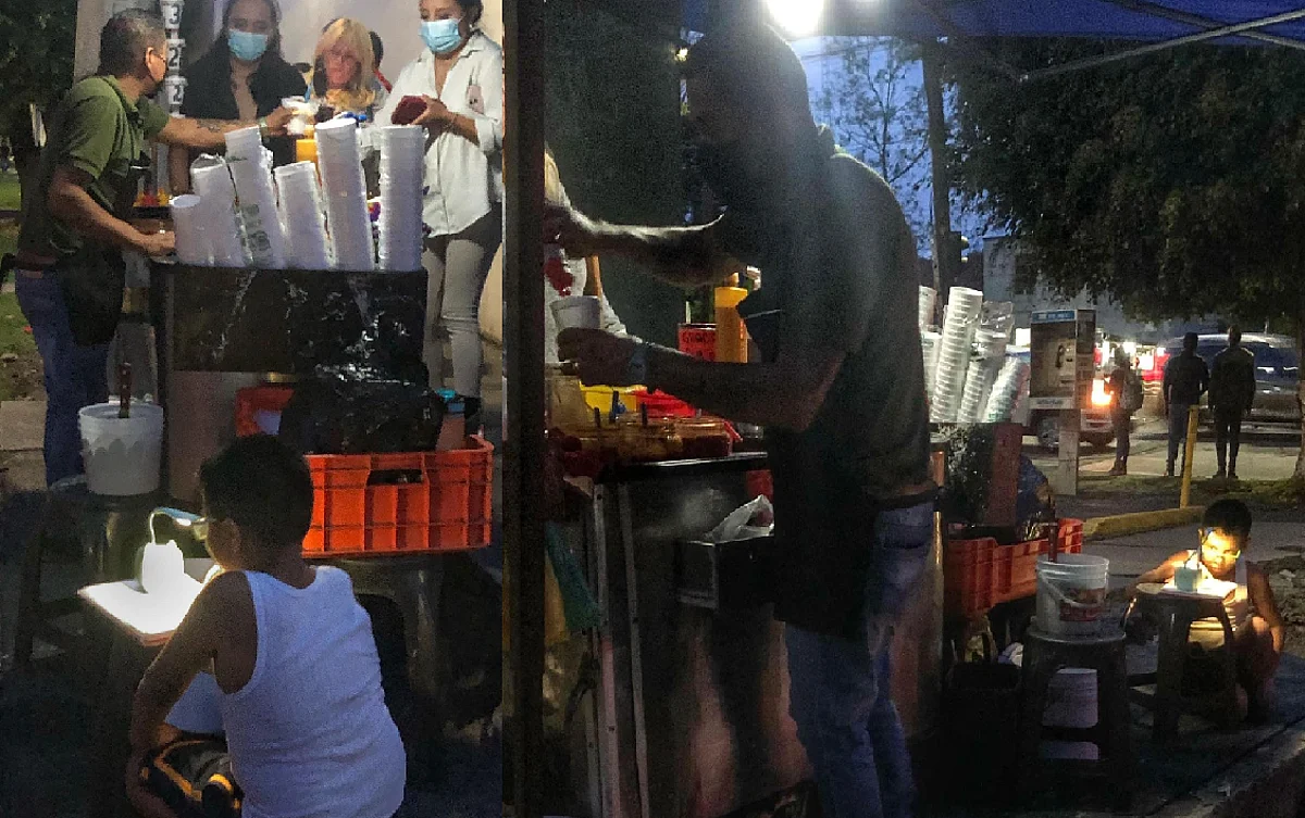 Niño moreliano ayuda a su papá a vender elotes mientras hace su tarea
