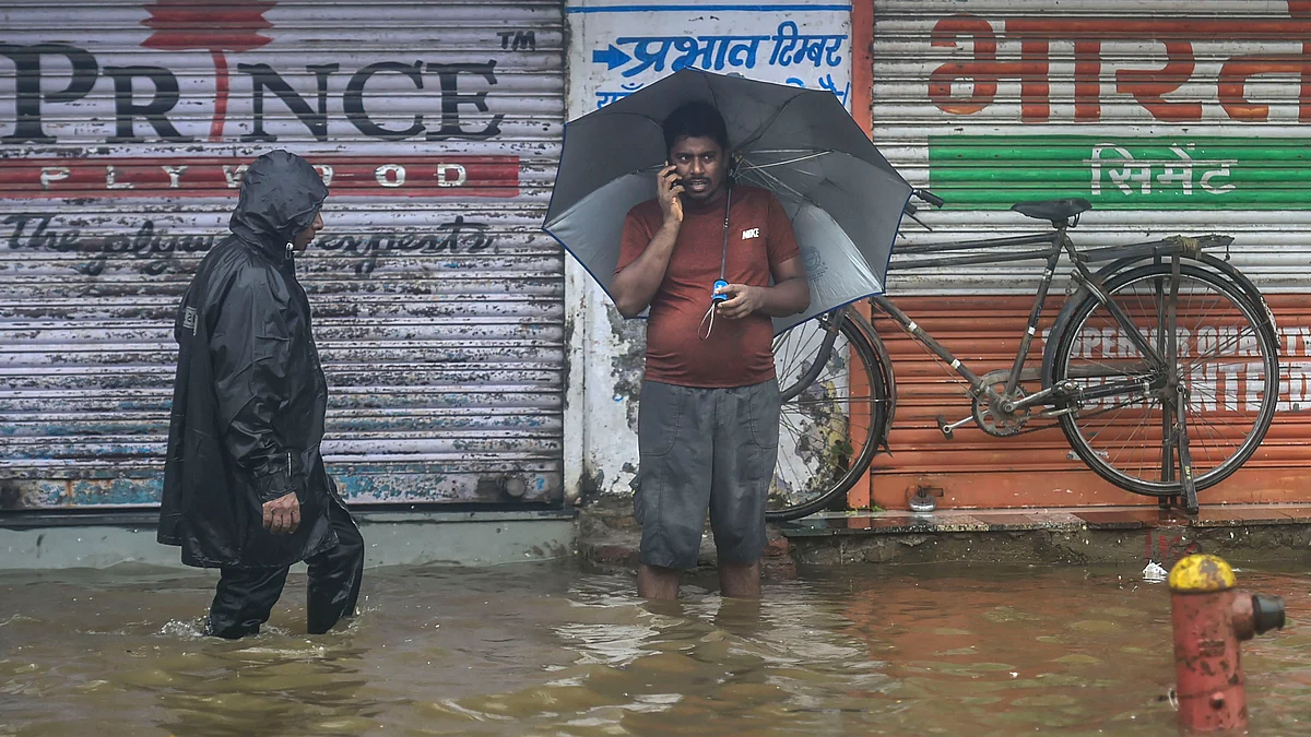 Pedestrians wade through a waterlogged street during monsoon rain, in Mumbai (PTI)