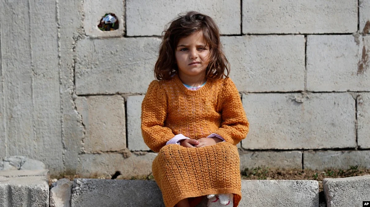 A displaced Syrian girl sits outside her family's tent at a refugee camp in Bar Elias, Bekaa Valley, Lebanon, March 5, 2021.